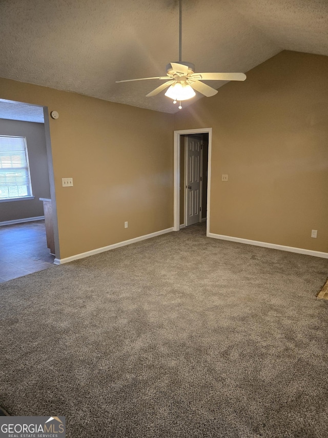 carpeted empty room featuring ceiling fan, vaulted ceiling, and a textured ceiling