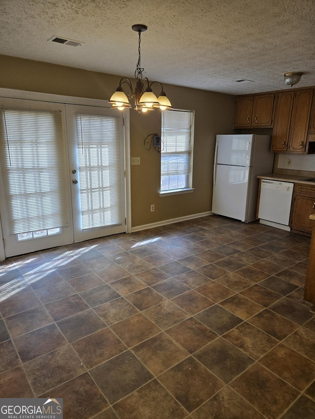 kitchen with pendant lighting, white appliances, a textured ceiling, and an inviting chandelier