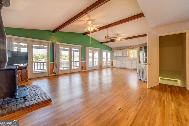 unfurnished living room featuring lofted ceiling with beams, ceiling fan, light wood-type flooring, and french doors