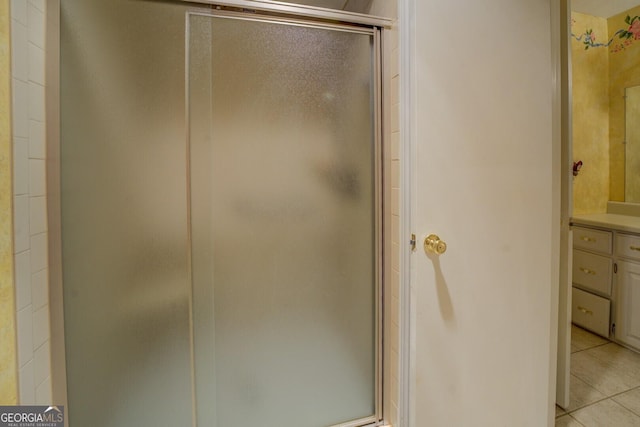 bathroom with tile patterned flooring, vanity, and walk in shower