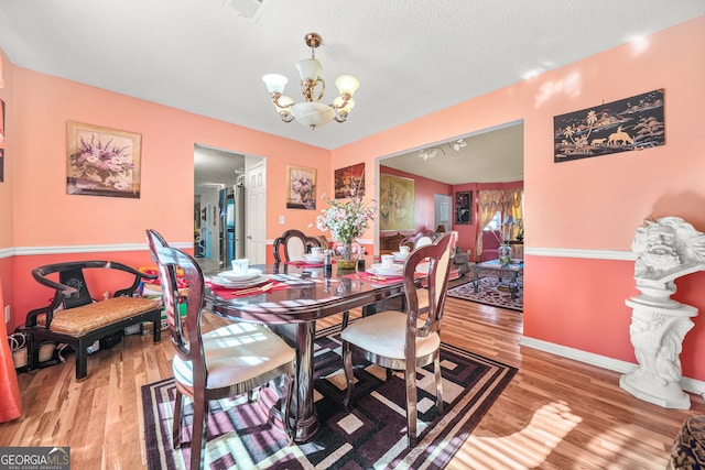 dining space featuring hardwood / wood-style floors, a textured ceiling, and an inviting chandelier