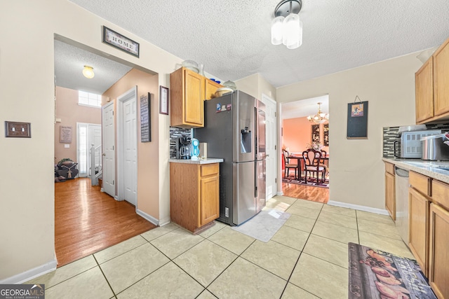 kitchen with an inviting chandelier, stainless steel fridge with ice dispenser, light tile patterned floors, and a textured ceiling