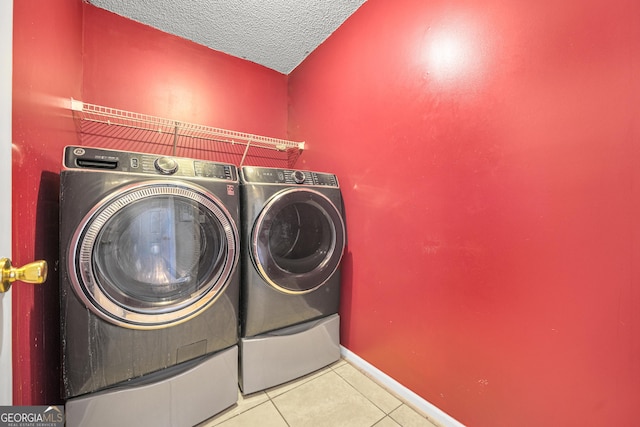 laundry room with washer and dryer, a textured ceiling, and light tile patterned flooring