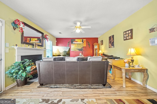 living room with ceiling fan, a textured ceiling, and light hardwood / wood-style floors