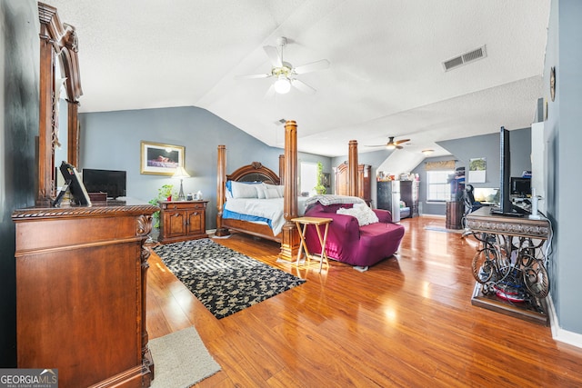 bedroom featuring light hardwood / wood-style flooring, ceiling fan, a textured ceiling, vaulted ceiling, and ornate columns