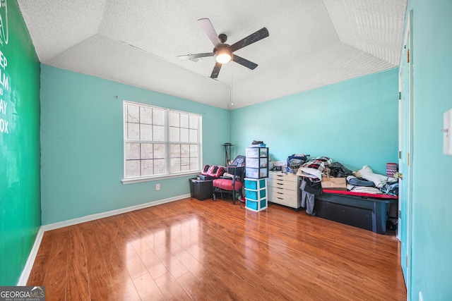 interior space with ceiling fan, hardwood / wood-style floors, a tray ceiling, a textured ceiling, and vaulted ceiling