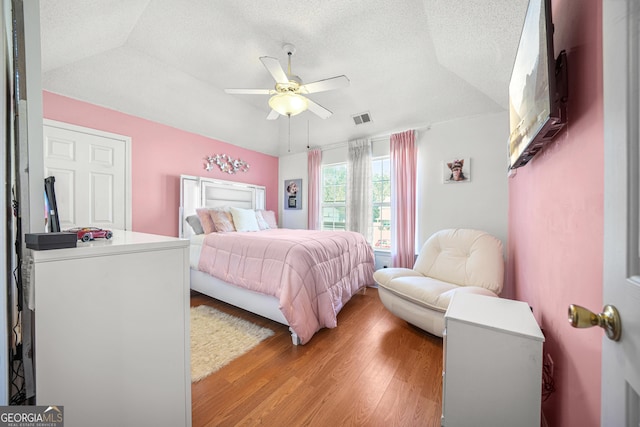 bedroom featuring ceiling fan, vaulted ceiling, a textured ceiling, and light wood-type flooring