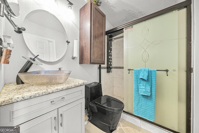 bathroom featuring vanity, a shower with door, and a textured ceiling