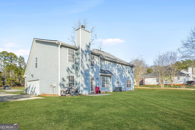 rear view of property with cooling unit, a garage, and a yard