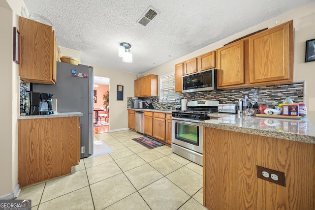 kitchen featuring sink, light tile patterned floors, appliances with stainless steel finishes, light stone countertops, and backsplash