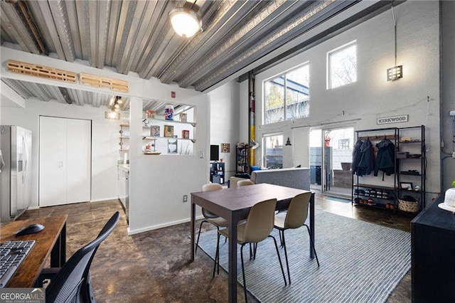 dining room featuring beamed ceiling and a towering ceiling