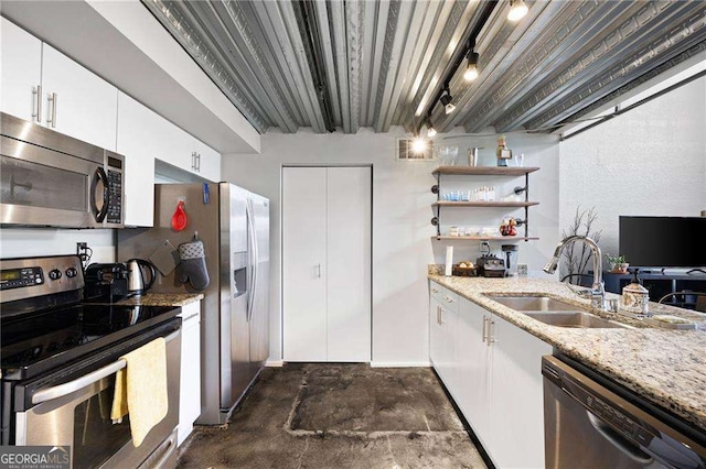 kitchen with stainless steel appliances, white cabinetry, sink, and light stone counters