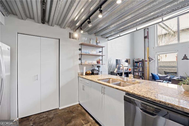 kitchen with appliances with stainless steel finishes, sink, white cabinets, light stone countertops, and track lighting