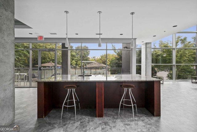 kitchen featuring pendant lighting, light stone countertops, and expansive windows