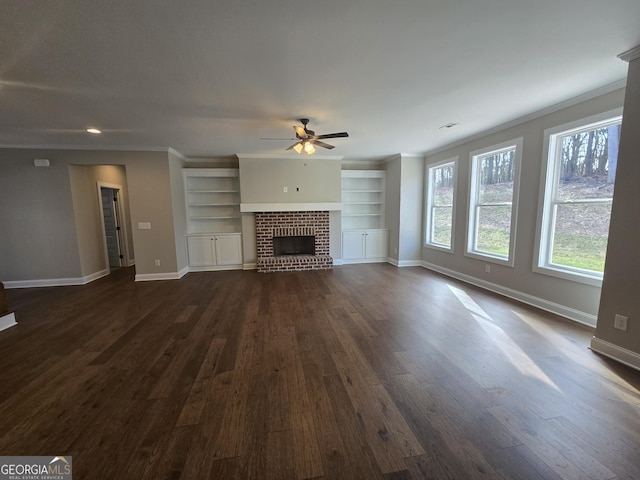 unfurnished living room with dark wood-type flooring, ceiling fan, ornamental molding, and a brick fireplace