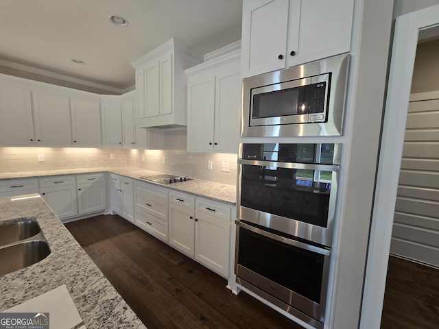 kitchen with white cabinetry, light stone countertops, decorative backsplash, and stainless steel appliances