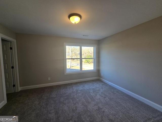 unfurnished room featuring dark colored carpet