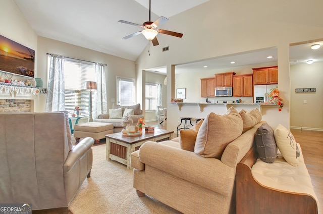 living room with ceiling fan, high vaulted ceiling, and light hardwood / wood-style floors