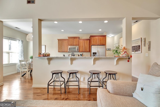 kitchen with a breakfast bar area, light hardwood / wood-style floors, kitchen peninsula, and appliances with stainless steel finishes