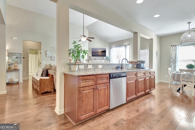 kitchen featuring sink, hanging light fixtures, stainless steel dishwasher, light stone countertops, and light hardwood / wood-style floors