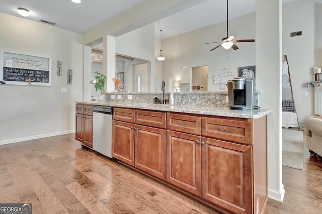 kitchen featuring pendant lighting, sink, light stone counters, stainless steel dishwasher, and light wood-type flooring