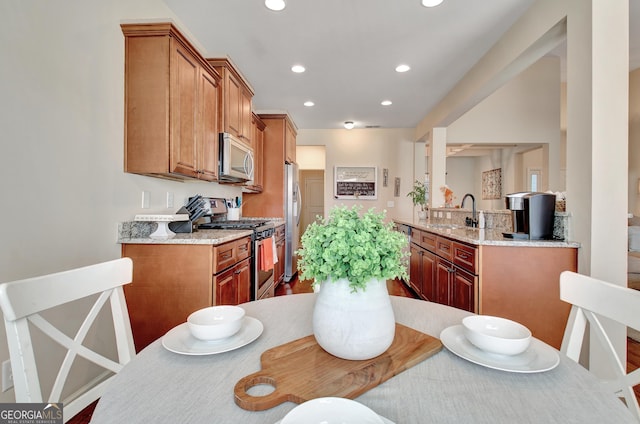 kitchen with sink, light stone countertops, and appliances with stainless steel finishes