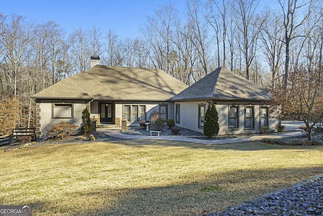 back of house featuring a lawn, a shingled roof, a chimney, and stucco siding