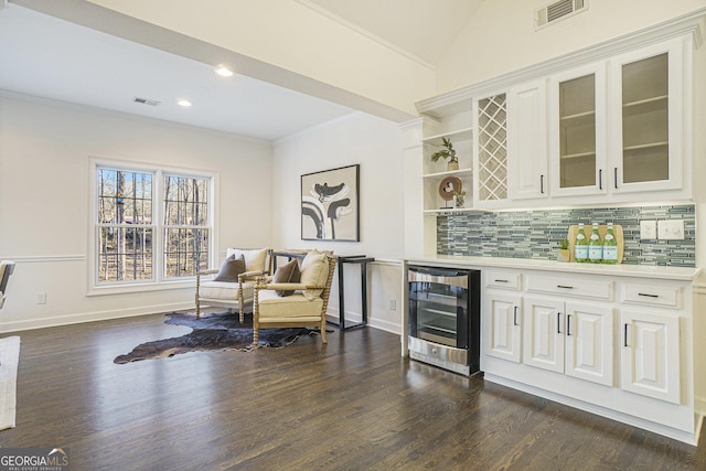 bar with beverage cooler, visible vents, a bar, crown molding, and dark wood-style flooring