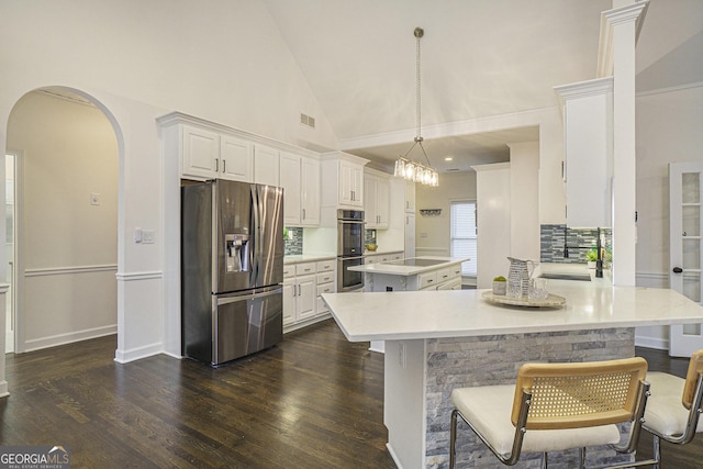 kitchen with dark wood-style floors, arched walkways, visible vents, a kitchen island, and appliances with stainless steel finishes