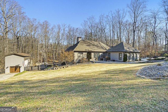 exterior space with fence, a front lawn, an outbuilding, and a chimney