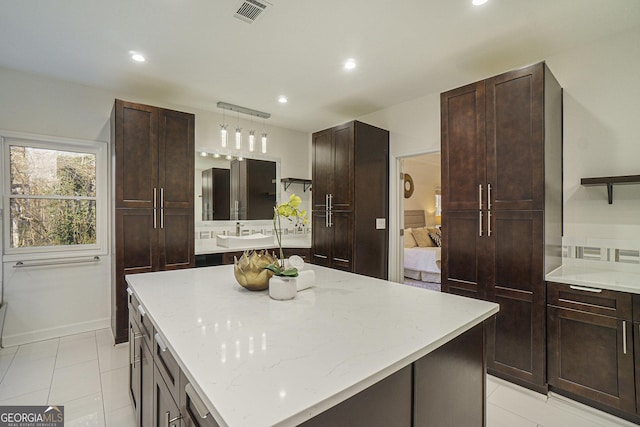 kitchen with recessed lighting, a kitchen island, visible vents, and light stone counters