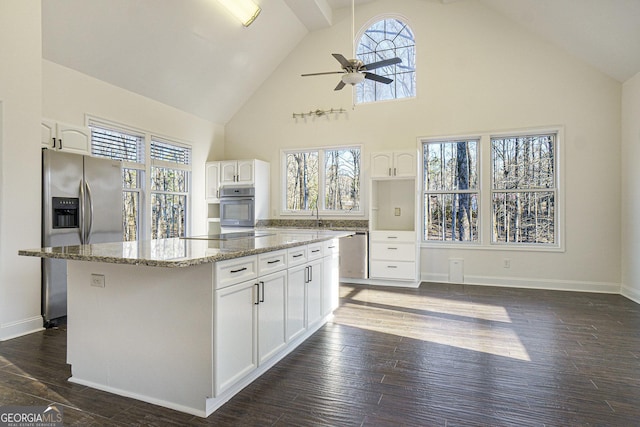 kitchen featuring stainless steel appliances, dark wood-style flooring, a ceiling fan, light stone countertops, and high vaulted ceiling