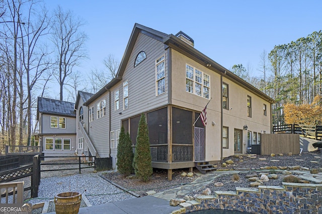 rear view of house with a chimney, fence, and a sunroom