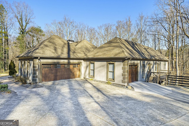 view of front of property featuring a garage, driveway, a shingled roof, and stucco siding