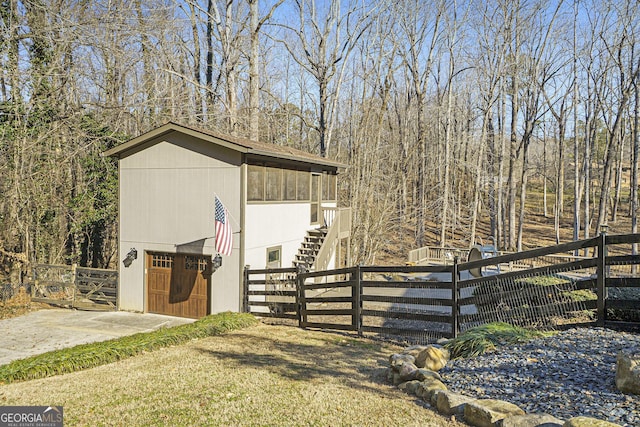 exterior space featuring a gate, concrete driveway, a garage, fence private yard, and stairs
