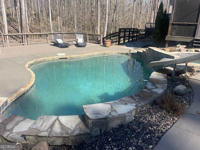 view of swimming pool featuring a fenced in pool, a water slide, and a deck