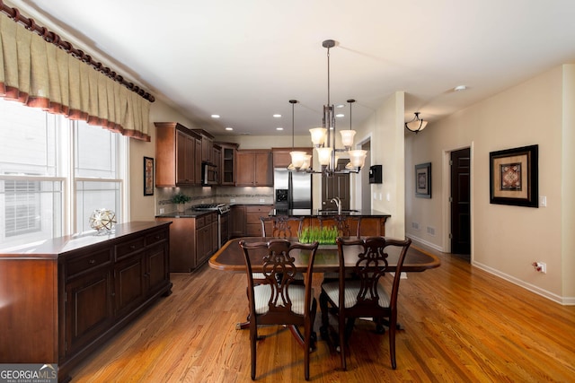 dining room featuring recessed lighting, light wood-type flooring, an inviting chandelier, and baseboards