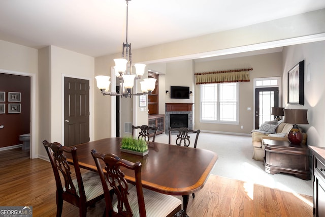 dining space with a brick fireplace, light wood-style flooring, visible vents, and baseboards