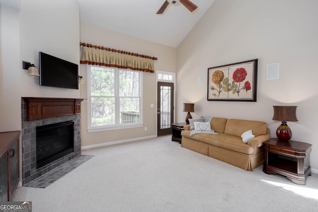 living area featuring baseboards, light colored carpet, a fireplace with flush hearth, ceiling fan, and high vaulted ceiling