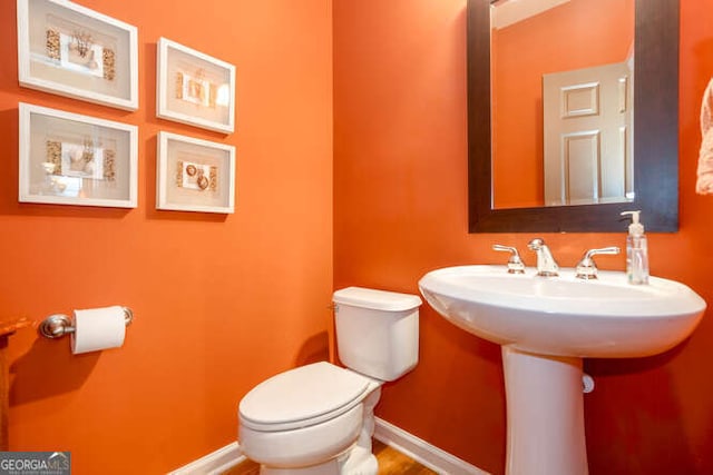 half bathroom featuring baseboards and toilet