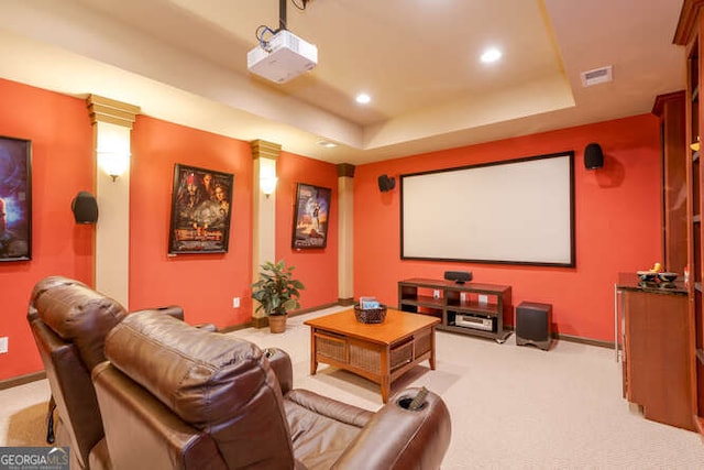 cinema room featuring a raised ceiling, light carpet, visible vents, and baseboards