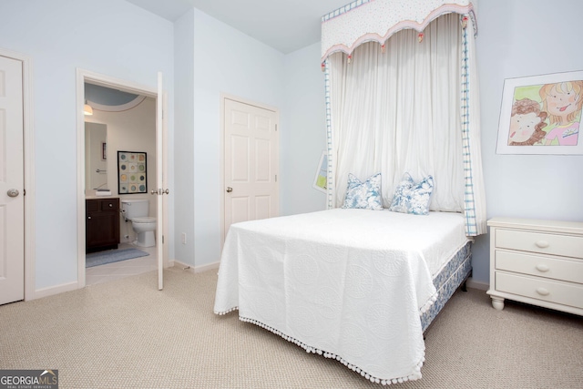 bedroom with light colored carpet, baseboards, and ensuite bathroom