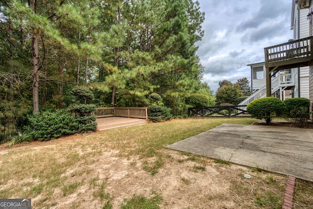 view of yard with a patio area, stairs, and a wooden deck