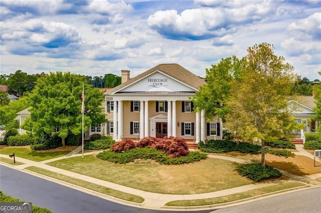 greek revival house with a front yard and a chimney