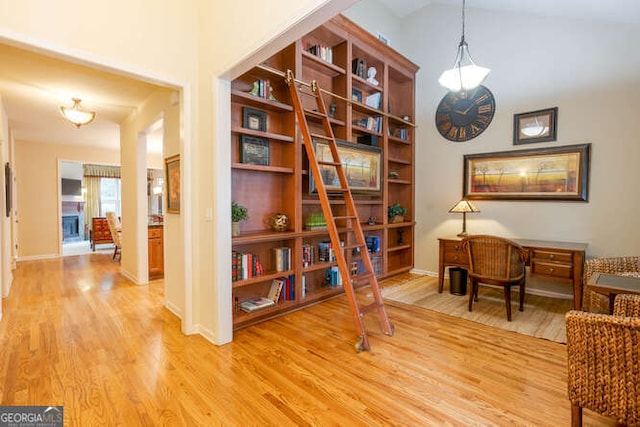 living area featuring baseboards, vaulted ceiling, and light wood finished floors