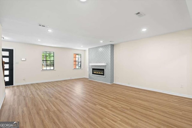 unfurnished living room with light hardwood / wood-style floors and a large fireplace