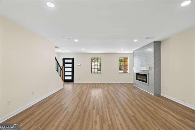 unfurnished living room featuring a large fireplace and light hardwood / wood-style floors