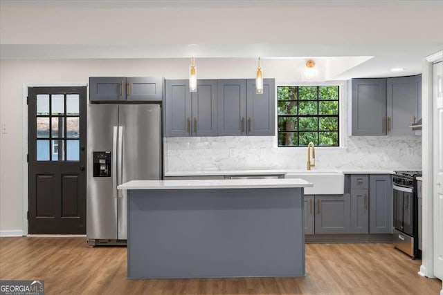 kitchen featuring gray cabinets, decorative light fixtures, sink, light hardwood / wood-style floors, and stainless steel appliances