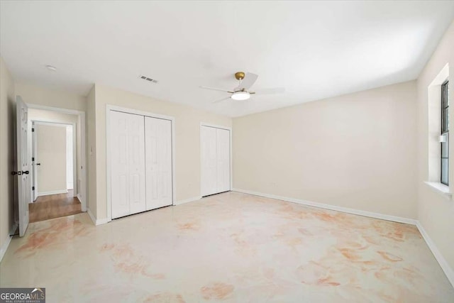 unfurnished bedroom with multiple closets and ceiling fan