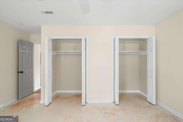 unfurnished bedroom with two closets and ceiling fan